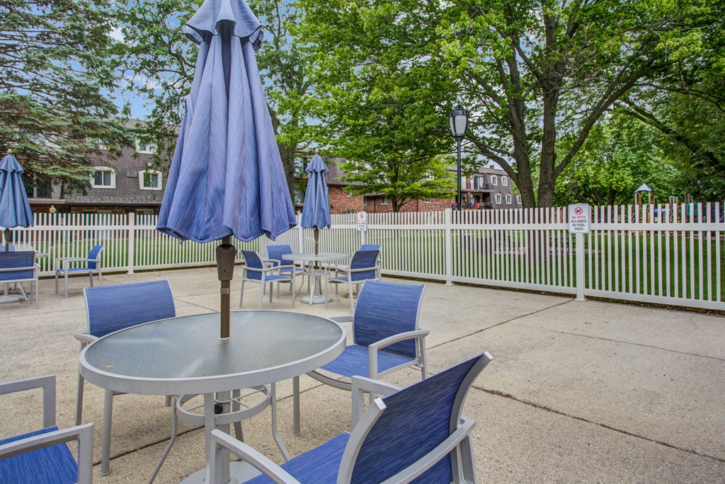 a patio with tables and chairs and an umbrella