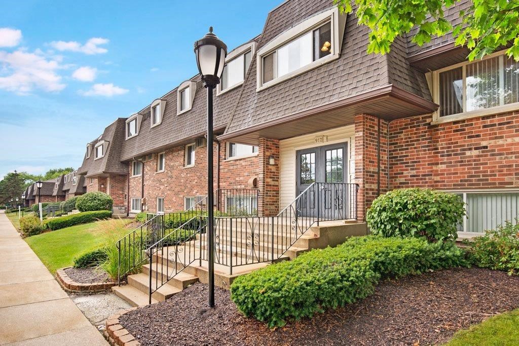 the front of a brick apartment building with stairs and a sidewalk