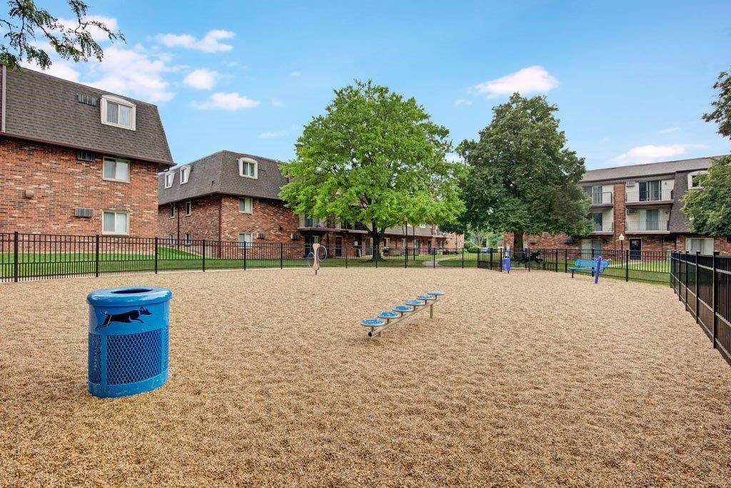 a dog park with a bench and a trash can