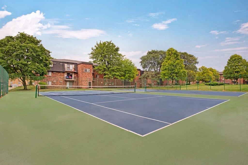 a tennis court with a house in the background