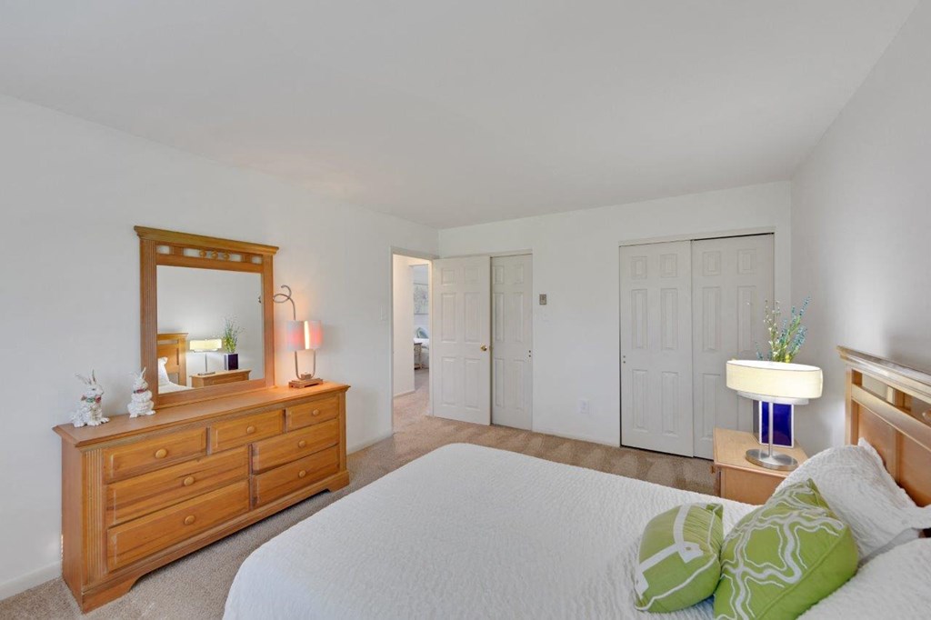 a bedroom with a bed and a dresser with a mirror