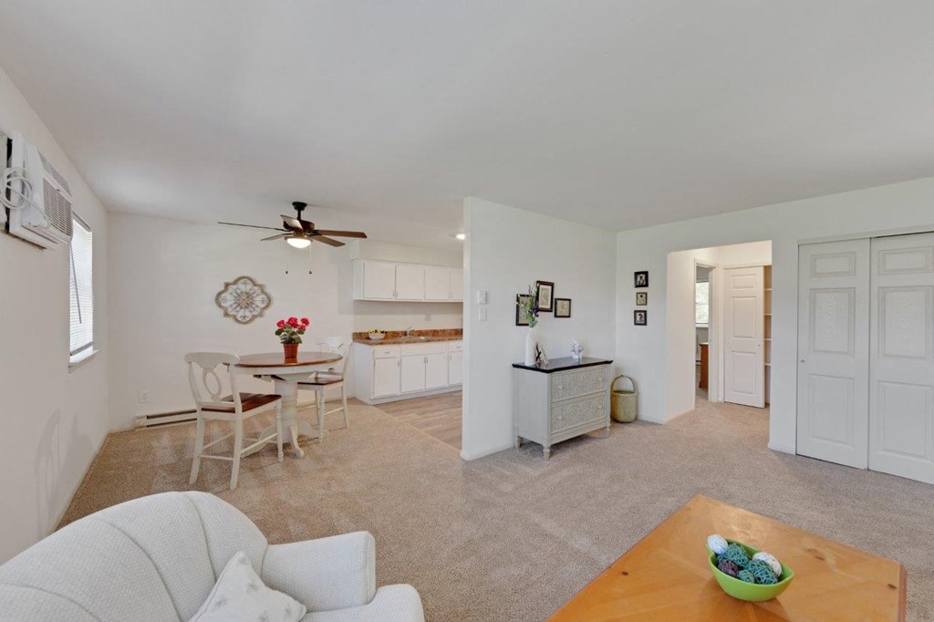 a living room and dining room with a kitchen and a ceiling fan