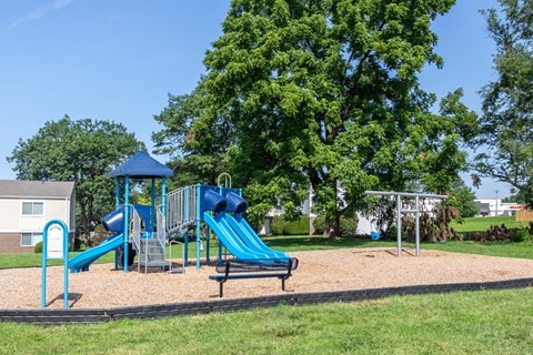 A playground with a blue slide and a bench.