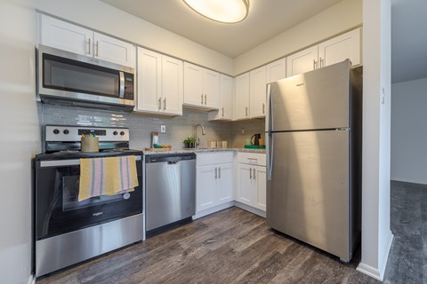 A kitchen with a stainless steel refrigerator, microwave, oven, and cabinets.