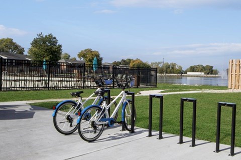 two bikes parked at a bike rack next to a lake