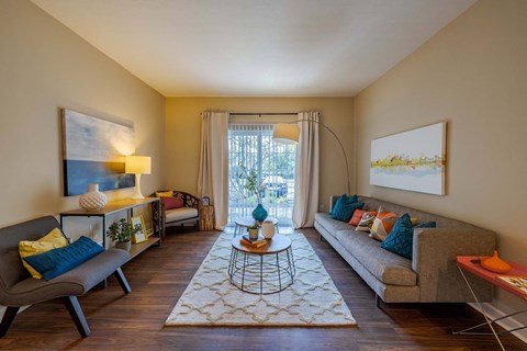 A living room with a grey couch, a coffee table, and a painting on the wall.