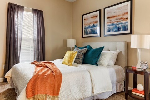 A bedroom with a large bed covered in a white comforter and a blanket draped over the side.