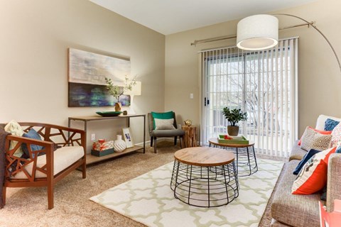 A living room with a wooden chair, a sofa, a coffee table, and a painting on the wall.