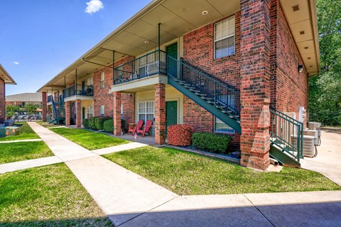 A red brick building with a green staircase and railings.
