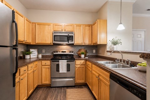 A kitchen with wooden cabinets and a stainless steel refrigerator.