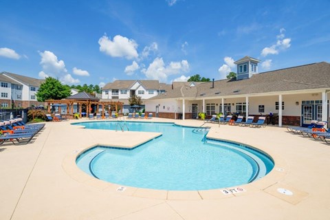 A large swimming pool in front of a building with a gazebo.