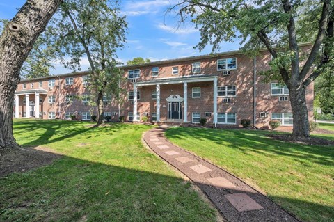 the front of a brick building with grass and trees