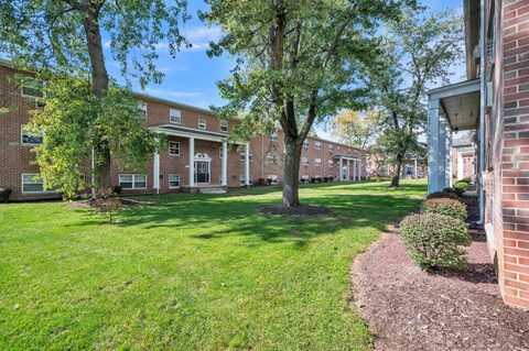 a brick building with green grass and trees