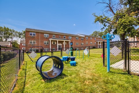 A playground with a blue slide and a black fence in front of a brick building.