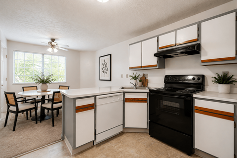 A kitchen with black and white cabinets and a black stove top oven.