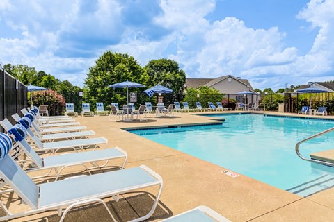 A pool with sun loungers and umbrellas.