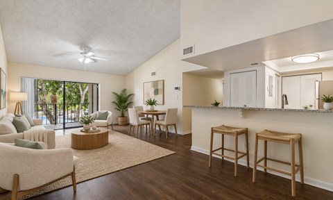 A living room with a white couch, wooden chairs, and a bar area.