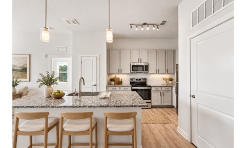 A kitchen with a granite countertop and wooden chairs.