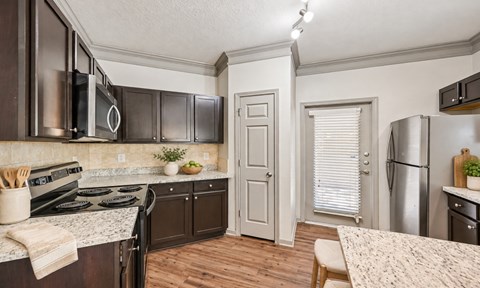 A kitchen with dark brown cabinets and a white door.