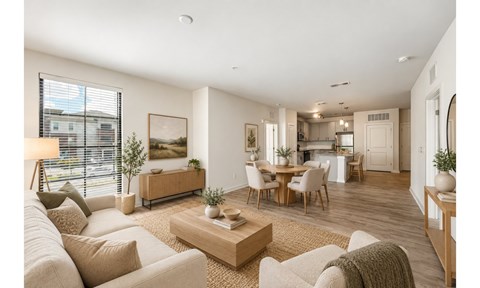 A well-lit, modern living room with a large sofa, a coffee table, and a dining area in the background.