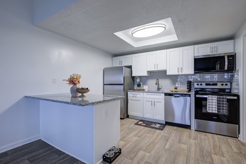 A kitchen with white cabinets and a granite countertop.