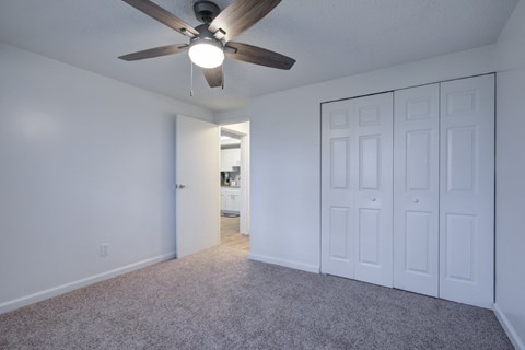 A room with a ceiling fan and carpeted floor.