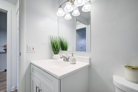 A white bathroom vanity with a mirror and lights above it.