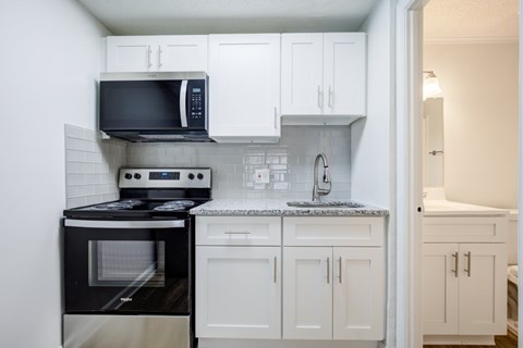 A kitchen with black appliances and white cabinets.