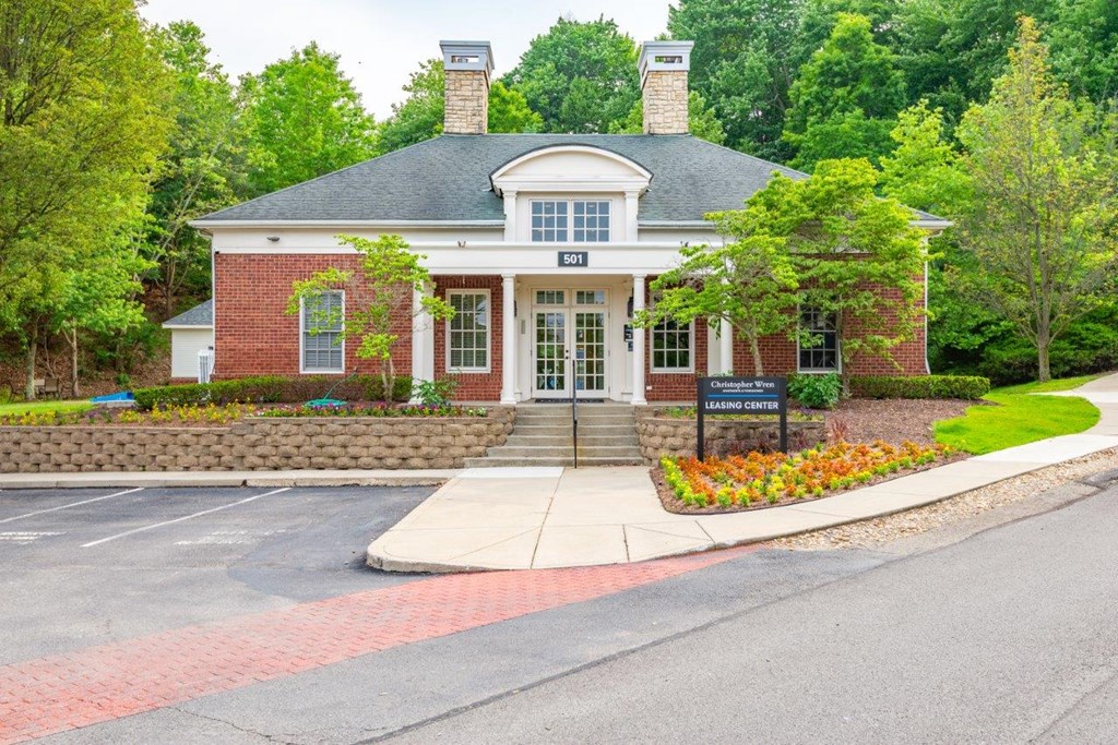 a red brick building with white trim and a black sign in front of it