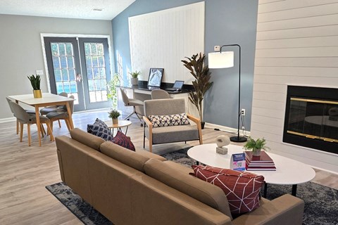 A living room with a brown couch, a white coffee table, and a fireplace.