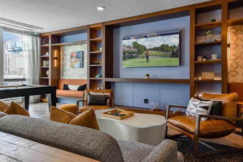 A living room with a grey sofa, a coffee table, and a television playing a golf game.