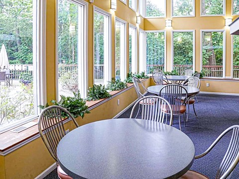 A round table with chairs in front of a window with a view of a garden.