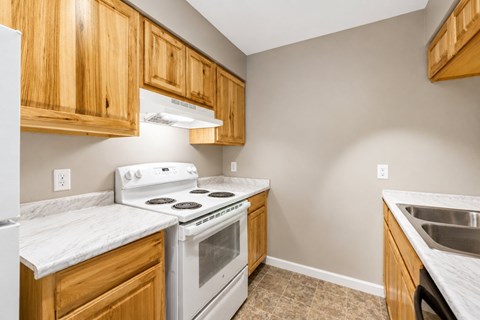 A kitchen with wooden cabinets and a white stove top oven.