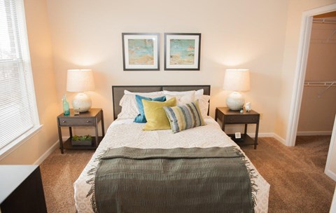 A bedroom with a large bed and two nightstands with lamps.
