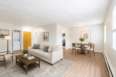 A living room with a white couch, a coffee table, and a dining table.