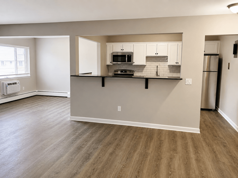 A kitchen with white cabinets and a wooden floor.