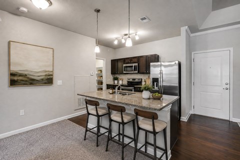 A kitchen with a granite countertop and bar stools.