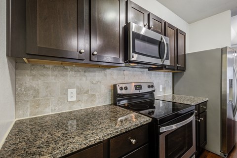an updated kitchen with granite counter tops and black appliances
