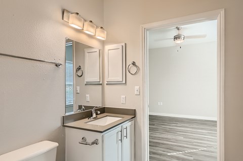 A bathroom with a white tub, sink, and mirror.