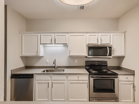 A kitchen with white cabinets and stainless steel appliances.