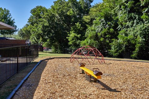 A playground with a red swing set and a yellow slide.