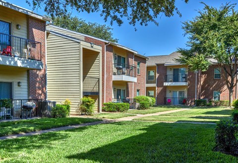 A row of apartment buildings with green lawns in front.