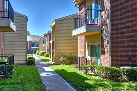 A row of apartment buildings with balconies and green lawns.