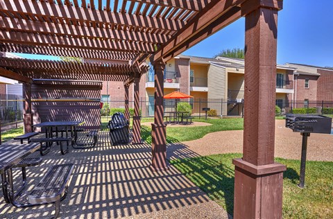A patio with a table and chairs under a pergola.