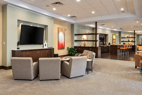 A spacious waiting room with a television, comfortable seating, and a bar area.