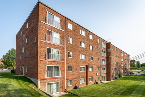 A red brick apartment building with white balconies and windows.