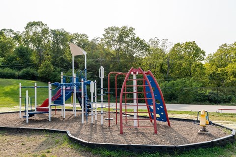 A playground with a red and blue slide and a yellow flag.