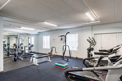 A gym with a variety of equipment including treadmills, weights, and exercise machines.