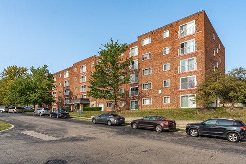 A red brick apartment building with cars parked in front.