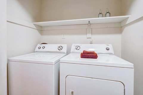 Two white washing machines in a small laundry room.